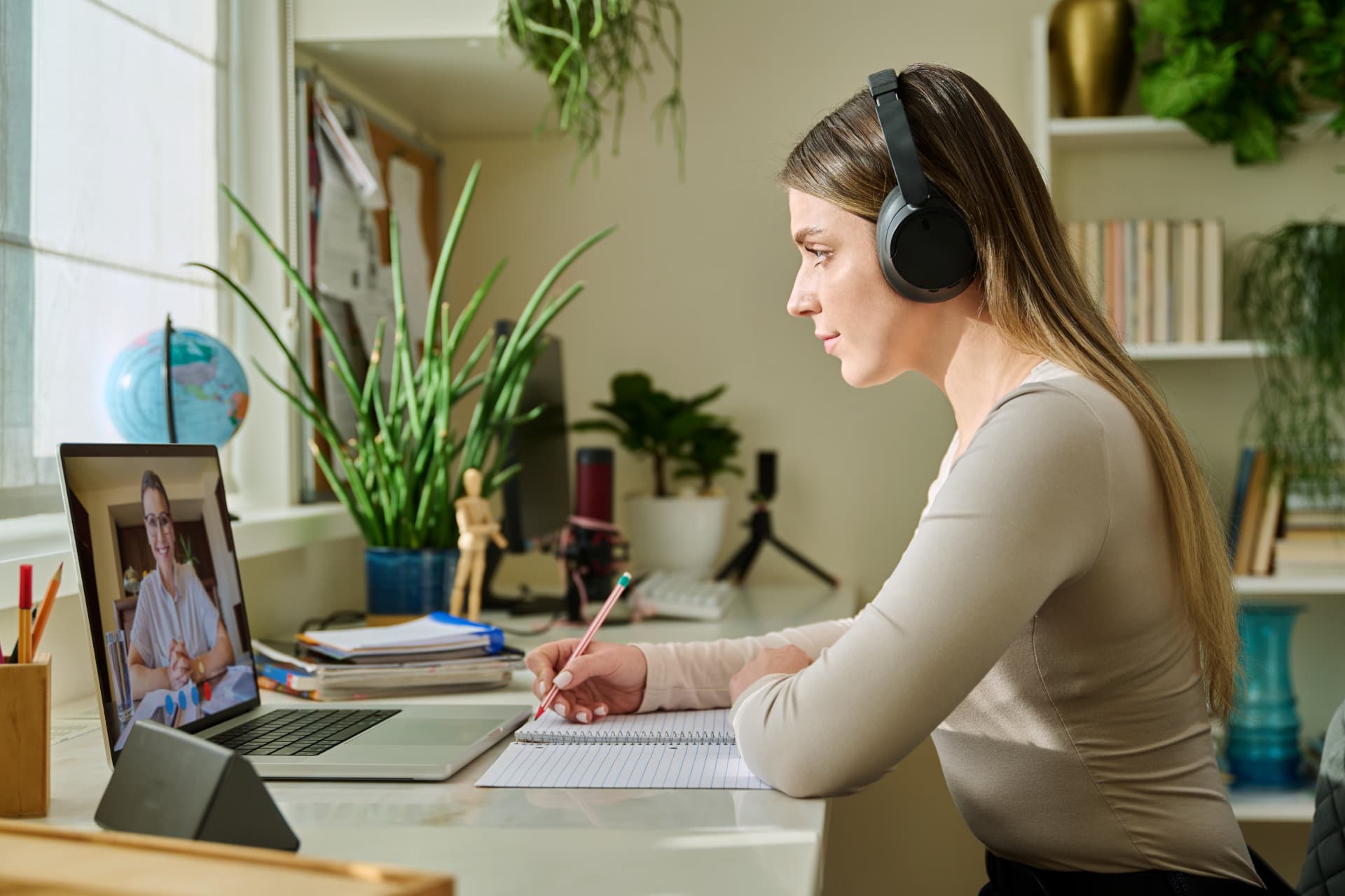 A learner wearing headphones and studying online at home